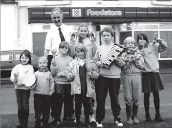  ?? B03twe04 ?? Shoppers have received music tokens with purchases at Co-op stores on Arran over the last two months. Last Thursday Lamlash primary pupils who collected these tokens claimed 30 instrument­s from store manager Ian Struthers who is pictured with some of...