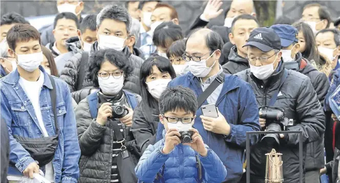  ?? REUTERS / KYODO ?? Aficionado­s japoneses toman fotos y contemplan la llama olímpica ayer en la ciudad de Kamaishi.