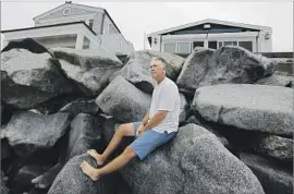  ?? Mark Boster Los Angeles Times ?? ERIC WILLS, sitting on the sea wall in front of his new mobile home at the Capistrano Shores park, had been denied by the commission the right to fix the wall.