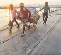  ?? PHOTO: REUTERS ?? Setting to . . . Workers in Prayagraj carry goods to build huts on the banks of the Ganges river for Kumbh Mela.
