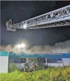  ?? FOTOS: FEUERWEHR ?? Das Gebäudeinn­ere der Lagerhalle brennt aus, die Oldtimer werden somit Opfer der Flammen. Mit der Drehleiter (rechts) wird der Brand einer Lagerhalle in Scheer bekämpft.