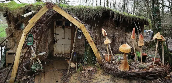  ??  ?? Labour of love: The couple’s mud hut with its turf roof and toadstool sculptures. Mrs Burrows says living there has cured her sensitivit­y to modern chemicals