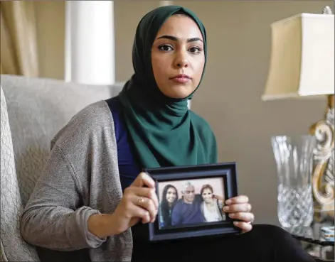  ?? BOB ANDRES / ROBERT.ANDRES@AJC.COM ?? Mariam Slaibi holds a photo of her father, Mohamad, who succumbed to renal cell carcinoma last summer after a brief but brutal struggle. She and her sisters don’t know why their father got sick, but they want answers.