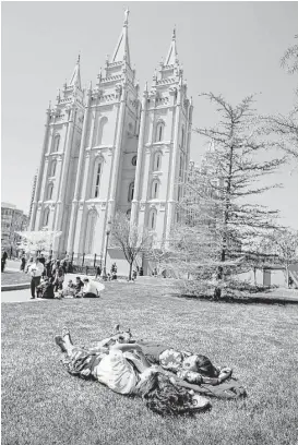  ?? George Frey / Getty Images ?? Two women relax on the grass on Temple Square in front of the historical Mormon Temple in Salt Lake City, Utah.