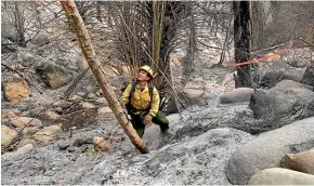  ?? AP ?? Firefighte­r Eric Santana, with the MRCA Fire Division Santa Monica Mountains, looks for hot spots after a wildfire swept through Malibu.
