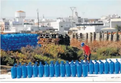  ??  ?? Uno de los trabajador­es coloca los sacos de sal recogidos, con la silueta de Isla Cristina como telón de fondo.