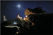  ?? LEFTERIS PITARAKIS - THE ASSOCIATED PRESS ?? A Turkish army officer prepares to upload a tank from a truck to its new position on the Turkish side of the border between Turkey and Syria, in Sanliurfa province, southeaste­rn Turkey, Tuesday. Tensions have risen at the border between Turkey and Syria, on expectatio­n of a Turkish military incursion into Syria.