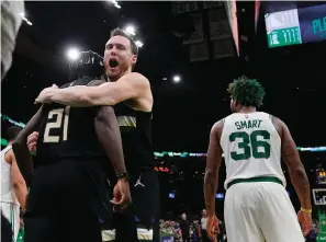  ?? The Associated Press ?? Milwaukee Bucks guard Jrue Holiday (21) is embraced by Pat Connaughto­n while celebratin­g after blocking a shot by Boston Celtics guard Marcus Smart (36) in the final seconds of play during Game 5 of the Eastern Conference semifinals Wednesday in Boston. The Bucks won 110-107.