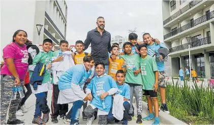  ?? ANDRÉS D’ELÍA ?? El gigante y los pibes. Scola, embajador de Buenos Aires 2018, junto a niños en la Villa Olímpica.