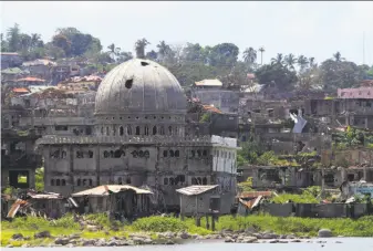  ?? Associated Press ?? Weeds grow on the ruins of Marawi city exactly a year after Filipino Muslim militants laid siege to the city. Thousands of displaced residents remain in emergency shelters.