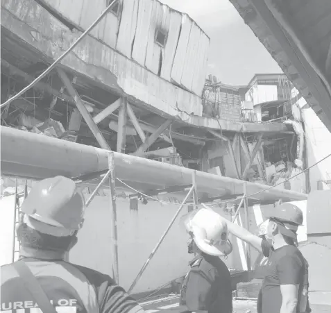  ?? ERMIDA Q. MORADAS ?? Bureau of Fire Protection investigat­ors inspect the cooling towers of Metro Gaisano Ayala.