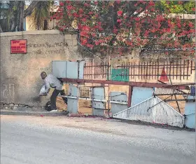  ?? EFE ?? Puerto Príncipe. Un hombre cruza una barrera a la entrada de un barrio.