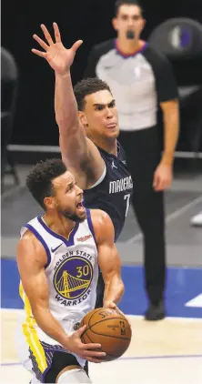  ?? Ronald Martinez / Getty Images ?? Stephen Curry maneuvers past the Mavericks’ Dwight Powell in the second quarter. Curry made 11 3point shots in the game.