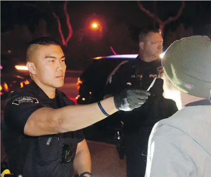  ?? BILL ALKOFER/THE ORANGE COUNTY REGISTER FILES ?? Police in Fullerton, Calif., conduct a field sobriety test on a driver suspected of driving while impaired by marijuana. One component is to watch the subject’s eyes while he follows the movement of the pen.