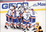  ?? Gene J. Puskar / Associated Press ?? The Penguins’ John Marino, bottom right, skates to the locker room as the Islanders celebrate a winning overtime goal by Kyle Palmieri in Game 1 of a Stanley Cup first-round playoff series on Sunday in Pittsburgh.