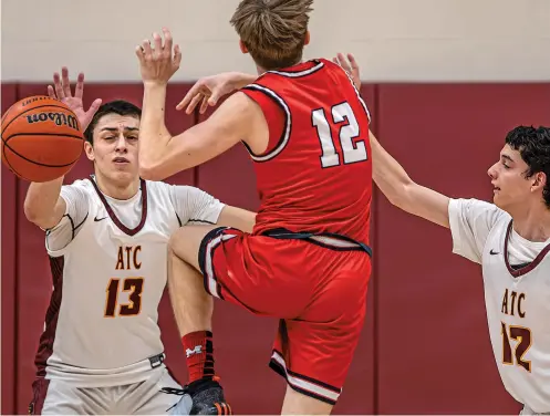  ?? JIM WEBER/NEW MEXICAN FILE PHOTO ?? The Academy for Technology and the Classics’ Julian Bernardino, left, and Davion Martinez, right, block a drive by Menaul’s Kazimieras Giedraitis on Feb. 2 during the District 2-2A Tournament championsh­ip. The top-seeded Phoenix will play No. 16 Clayton at Pojoaque on Saturday in the state tournament.