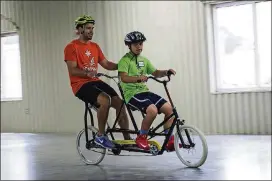  ??  ?? Alejandro Martin gets the feel for a bike with the help of Steven Smucker from I Can Shine. I Can Shine brings a tandem bike to help teach balancing.