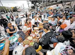  ?? ALEJANDRO TAMAYO/SAN DIEGO UNION TRIBUNE ?? Volunteers hand out meals Monday at El Chapparal border crossing in Tijuana, Mexico, where about 200 people from Central America are hoping to gain asylum in the U.S.