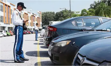  ??  ?? Enforcemen­t officers from councils that have adopted the FlexiParki­ng app only need a smartphone to check if a motorist has paid for parking. — Sepang Municipal Council