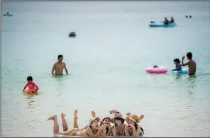  ?? The New York Times/NANCY BOROWICK ?? Tourists take a selfie in the waters of Tumon Bay on Guam earlier this month.