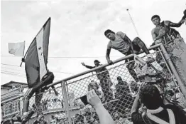  ?? JOHN MOORE/GETTY ?? Migrants scale a gate Friday separating Guatemala and Mexico. A caravan of migrants, mostly Hondurans, is trying to pass into Mexico en route to the United States.