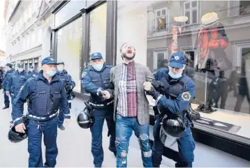  ?? PETR DAVID JOSEK/AP ?? Police detain a demonstrat­or Tuesday during a protest against vaccinatio­ns and coronaviru­s measures in Ljubljana, Slovenia. EU leaders planned to meet Tuesday in Kranj, Slovenia, to discuss tense relations with China and the security implicatio­ns of the U.S.-led exit from Afghanista­n, before taking part in a summit with Balkans leaders Wednesday.