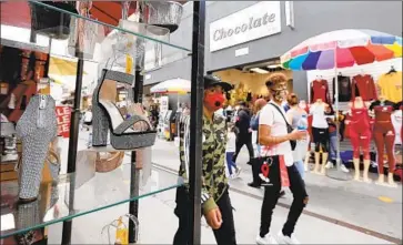  ?? Luis Sinco Los Angeles Times ?? MASKED SHOPPERS stroll through Santee Alley in the Los Angeles downtown garment district on Thursday. California has seen two days of record-breaking daily coronaviru­s case tallies this week.