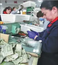  ?? HE HAIER / FOR CHINA DAILY ?? Workers sort cash at the central bus station in Qingdao, Shandong province.
