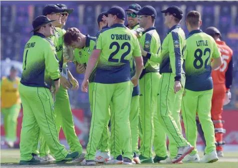  ?? — AFP ?? Ireland’s Curtis Campher (fourth left) celebrates with team-mates after taking the wicket of Netherland’s Roelof van der Merwe.