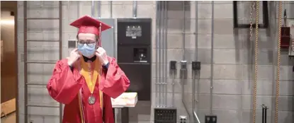  ?? SCOTT OLSON/GETTY IMAGES ?? A student removes his protective mask before walking across the stage to receive his diploma during a graduation ceremony in May at Bradley-Bourbonnai­s Community High School.