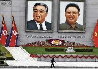  ?? Damir Sagolj - 16.abr.2017/Reuters ?? Homem passa por retratos do avô e do pai do atual líder norte-coreano em Pyongyang