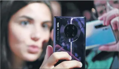  ?? LU YANG / XINHUA ?? A model holds the newly released Huawei Mate 30, a 5G smartphone, in Munich, Germany on Sept 20.