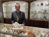  ?? PHOTOS BY PEG DEGRASSA = MEDIANEWS GROUP ?? Michael Cook, the owner of Walter J. Cook Jeweler in Paoli, stands in front of a showcase of silver baby goods, while showing one of the unique jewelry collection­s currently in stock at the shop.