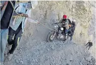  ??  ?? Road to ruin A motorcycle rider is inched across a treacherou­s mountain road in Spiti Valley in the Indian Himalayas after a landslide that left the route near impassable, teetering above a 200ft drop.