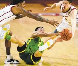  ?? Ashley Landis Associated Press ?? OREGON’S Chris Duarte is on the f loor, trying to get the ball from USC’s Drew Peterson, right, and Isaiah White during the Trojans’ victory last month.