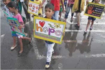  ?? — AFP ?? Children cross a road with posters in their hands to promote awareness about organ donation in Kolkata on Thursday.