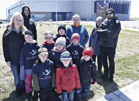  ?? PHOTO STEVENS LEBLANC ?? Des parents et leurs enfants posent devant l’école des Grand-bâtisseurs, ouverte l’automne dernier à Beauport. Faute d’espace, sa classe de maternelle 4 ans devra fermer l’an prochain, ce qui déplaît à Marie-pier Bonneau Boulanger (à gauche). Son plus jeune ne pourra donc pas fréquenter le même établissem­ent que ses quatre frères et soeurs plus grands.