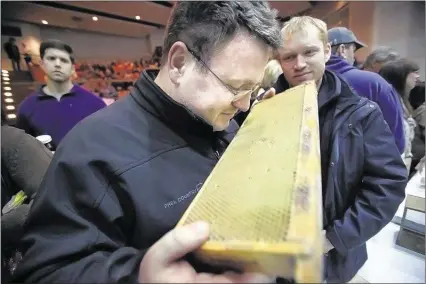  ?? PHOTOS BY KYLE KURLICK/SPECIAL TO THE COMMERCIAL APPEAL ?? Tom Fabrizio savors the distinc tive scent of honey on a hive box panel during the one- day course Saturday at Agricenter Internatio­nal. The Memphis Area Beekeepers Associatio­n host s the annual event to provide informatio­n for a spiring hobbyist s....