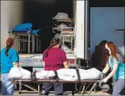  ?? Courtney Pedroza Getty Images ?? PIMA COUNTY medical examiner’s office workers move a body into a refrigerat­ed truck in Tucson.