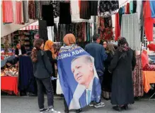  ?? ?? A woman caped in an election campaign flag for Turkish President Recep Tayyip Erdogan on her shoulders, shops at a local market, ahead of the May 28 presidenti­al runoff vote, in Istanbul, Turkey, on May 24.