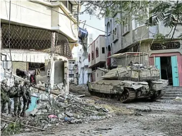  ?? /Reuters ?? Street by street: Israeli soldiers operate with a tank in the Shejaiya district of Gaza City. Israel on Wednesday reported 10 of its soldiers were killed in the month’s worst day for its armed forces, with most of the deaths happening in Shejaiya.