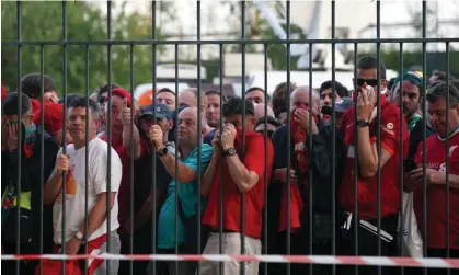  ?? Photograph: Peter Byrne/PA ?? Liverpool fans cover their faces due to police using teargas to disperse crowds as they queue outside the Stade de France.