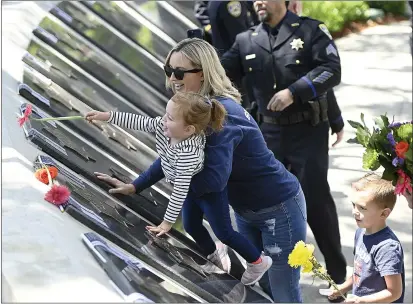  ?? PHOTOS BY JOEL ROSENBAUM — THE REPORTER ?? Jamie Capoot-Trujillo holds her 2-year-old daughter, Harper James, as she places a flower above the memorial star that bears the name of her grandfathe­r, James L Capoot, at the wall of fallen peace officers Wednesday at the conclusion of the 2022Peace Officers' Memorial Service in Fairfield. Jamie's son, Wally, 5, stands by her side. James Capoot, a police officer with the Vallejo Police Department, was killed in the line of duty Nov. 17, 2011.