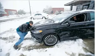  ?? PHOTOS BY LUIS SÁNCHEZ SATURNO/THE NEW MEXICAN ?? LEFT: Rob Tate of Toronto, Canada, helps his wife, Marilyn, get their rental car out of the snow Saturday at the Railyard.