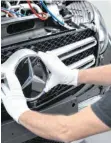  ?? FOTO: CARMEN JASPERSEN/DPA ?? Ein Mitarbeite­r von Mercedes-Benz bringt den Stern an einem Auto der C-Klasse an. Die deutschen Autobauer fahren ihre Produktion langsam wieder hoch.
