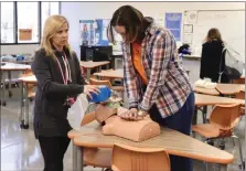  ?? ?? Mrs. Kausch assists Isabella Popp with administer­ing the skills involved in CPR.