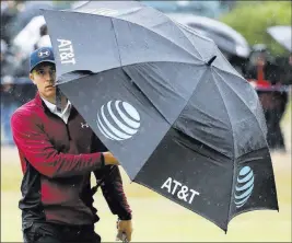  ?? Peter Morrison ?? The Associated Press Jordan Spieth wards off wind and rain as he walks the 18th fairway en route to a second-round 69 and a two-shot lead at Royal Birkdale.