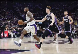  ?? LACHLAN CUNNINGHAM — GETTY IMAGES ?? Lakers star LeBron James leads a fastbreak against Sacramento's Kevin Huerter, center, during the second quarter at Golden 1Center on the 20th anniversar­y of his NBA debut.