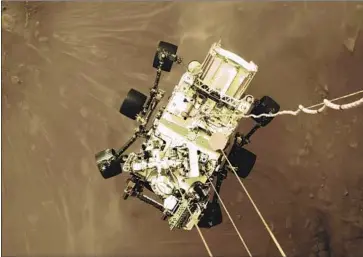  ?? NASA ?? THE PERSEVERAN­CE rover is lowered toward the surface of Mars. The image — one of several shared by NASA — gave Mars team members a sense of relief that the rover had made its grueling journey in one piece.