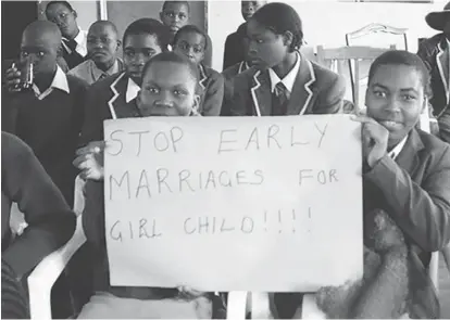  ??  ?? School children lift a placard denouncing child mariages